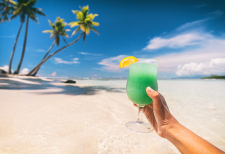 Blue Hawaiian drink cocktail woman drinking curacao liqueur on beach vacation travel in Caribbean destination. Summer fun lifestyle.の写真素材