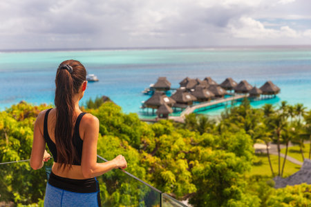 Luxury Bora Bora hotel resort woman tourist overlooking view of overwater bungalows villas on Tahiti ocean, French Polynesia.の写真素材