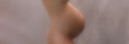 Pregnant woman belly closeup in shower. Beautiful naked out of focus blurred preagnancy body during pregnancy 3rd trimester. Maternity photo steam bath shower. Expectant woman panoramic bannerの写真素材