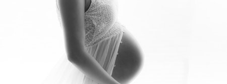 Pregnant woman maternity artistic photoshoot. Pregnancy profile portrait showing beautiful big belly baby bump third trimester. Woman expecting baby shot profile panoramic banner in black and whiteの写真素材
