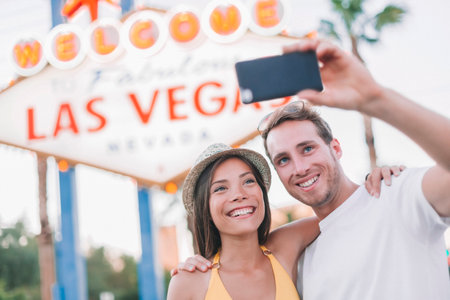 Las Vegas sign selfie young couple of tourists taking photo with phone at famous USA travel destination on summer vacationの写真素材
