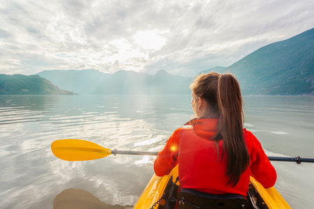 Woman kayaking paddling in kayak in fjord surrounded by mountains. People living healthy active outdoor lifestyle. From Howe Sound, Squamish, British Columbia, Canadaの写真素材