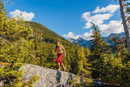 Running woman trail runner. Sport and fitness woman doing cross-country trail run ultra marathon training in mountains. Female athlete living healthy lifestyle. Squamish, British Columbia, Canada.の写真素材