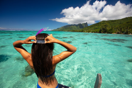 Beach travel vacation sport girl ready to snorkel in coral reefs of turquoise waters in Tahiti, French Polynesia. Image is completely unretouched. Authentic real people. Raw Imageの写真素材