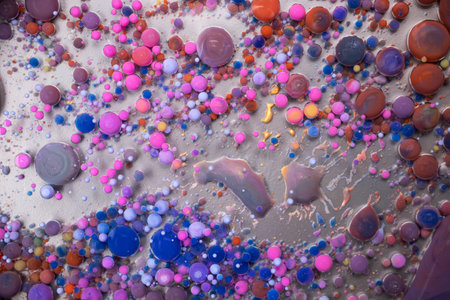 Acrylic paint balls abstract texture. Bright colors fluid, flowing wallpaper design. Purple, blue, pink and yellow liquids mix.の写真素材