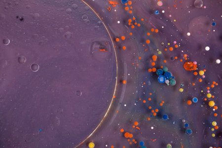 Acrylic paint balls abstract texture. Bright colors fluid, flowing wallpaper design. Purple, blue, pink and yellow liquids mix.の写真素材