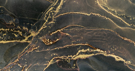 Intricate patterns created by alcohol ink on a smooth surface with shimmering gold accentsの写真素材