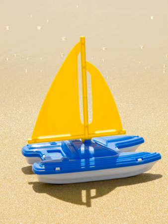 This is a photograph of a toy sailboat on the sandy beach of Newport Beach, California.の写真素材