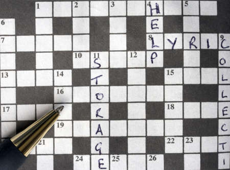 A pen on a crossword which has some clues solved.の写真素材