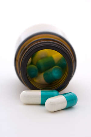 A pill bottle of medication, two of which have fallen outside the bottle.
