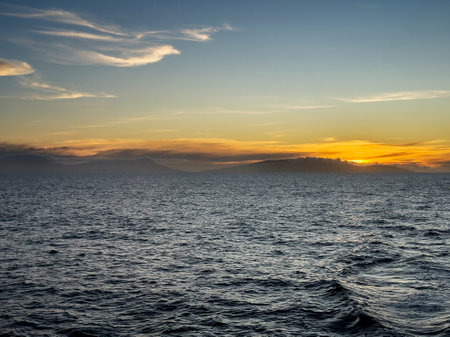 Sunset over the sea near the Falkland Islands with clouds and mountains in the backgroundの写真素材