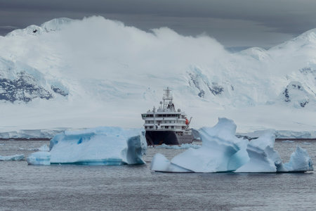 Antarctic landscape with icebergs, mountains, snow, and an expedition cruise ship in the ocean