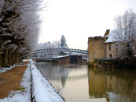 Snow-covered houses and metal footbridge on the towpath of the Briare canal in Montargisの写真素材