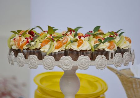 Muffins with butter cream and fruits on the festival plate