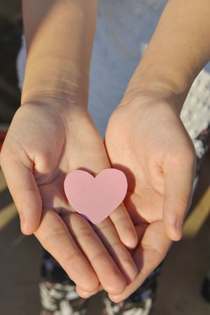 Pink paper heart on the girl's handsの写真素材