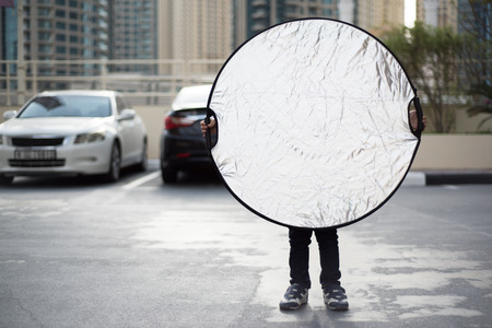 Funny Little Photographer's Assistant is Holding a Silver Reflectorの写真素材