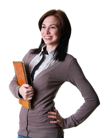 Isolated portrait on white of a young pretty girl woman wearing casual clothes striped shirt and pullover, holding a big text book and smiling with happy toothy smile, her hand on waistの写真素材
