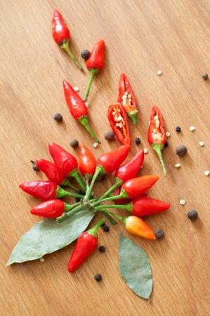 Still life of bunch of chili pepper, black pepper, nutmegs, peppercorn and bay leaves on the wooden texture table backgroundの写真素材