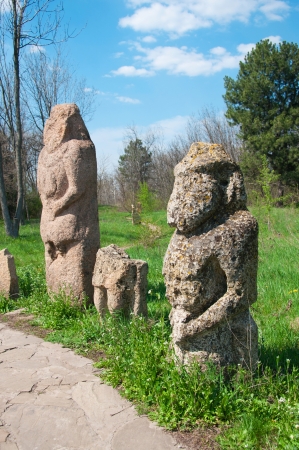 Historical Scythian monuments called kurgan stelae standing in nature against bright green grass, blue sky with cloudsの写真素材