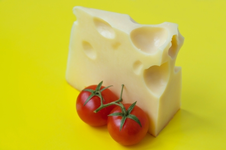 tomatoes with stems near a piece of cheeseの写真素材