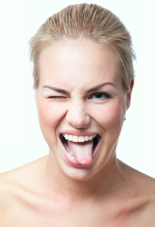 Funny cute blond woman making faces, showing her tongue, winking, looking at camera. Isolated on whiteの写真素材