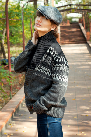 Young woman in boyish clothing posing, walking in the park over autumn sceneryの写真素材