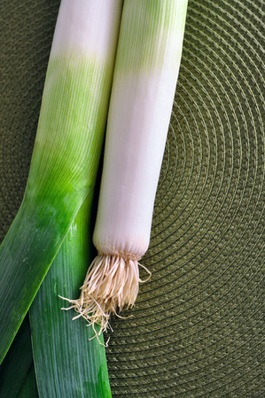 Fresh green leek onion stems against green background. Kitchen still lifeの写真素材