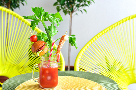 Fancy bloody mary cocktail served in a mason jar with a bite size burger, shrimp, celery stickの写真素材