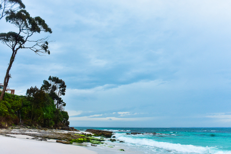 One of the most beautiful beaches in Australia with white sand on a moody rainy day, turquous water of the ocean, waves hit the shoreの写真素材