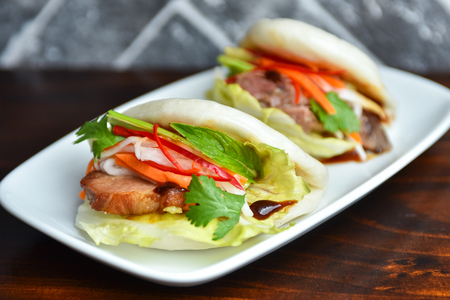 Fresh delicious pork steamed buns with BBQ sauce, coriander, mint, salad leaf and vegetalbles carrots, capsicumの写真素材