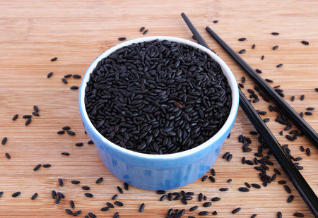 Uncooked black rice in blue bowl with black chopsticksの写真素材