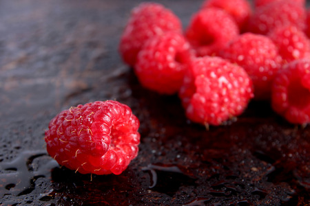 Raspberries in red bowl on brown background