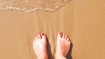 Female feet on the beach sand while relaxing.の写真素材