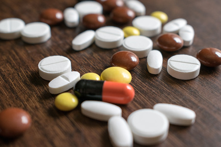 Multicolored tablets. Medical products to maintain good health and well-being. On a wooden background.の写真素材