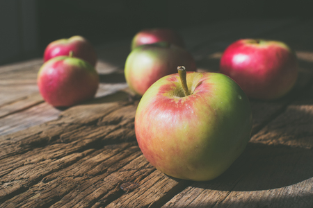 Photo of small red - green apples on a wooden background.の写真素材