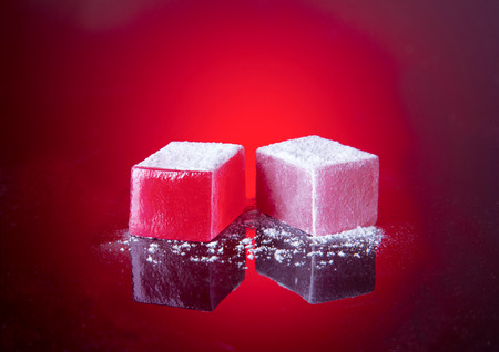 Marmalade sweets with filling and powdered sugar on a red background. Gelatin or marmalade candy.の写真素材