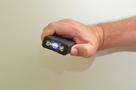 A taser held in a mans hand isolated on a white background