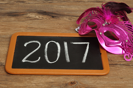 2017 written on a blackboard displayed with a pink maskの写真素材