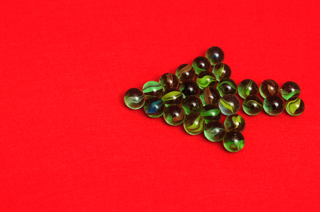 Marbles displayed in a arrow shape on red backgroundの写真素材
