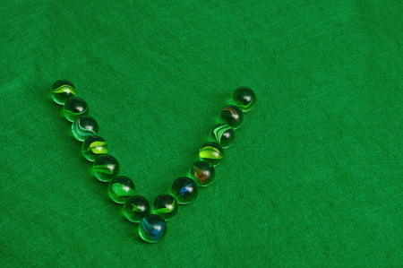 The letter V made out of marbles on a green backgroundの写真素材