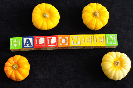 Halloween spelled with alphabet blocks with pumpkins against a black backgroundの写真素材