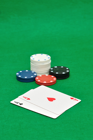 Different poker chips with two aces on a green background
