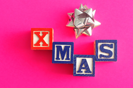 Xmas spelled with Alphabet blocks on a pink background with a silver gift bowの写真素材