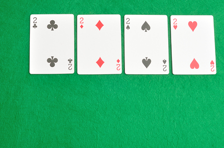 The different suit of the number 2 cards in a deck of cards displayed on a green background