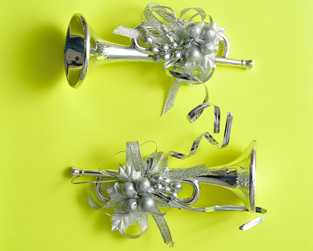 Silver trumpets to decorate a Christmas tree isolated against a yellow background