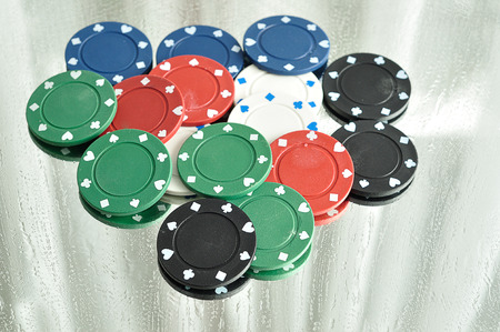 A stack of poker chips reflecting in a mirror that is stained with water drops