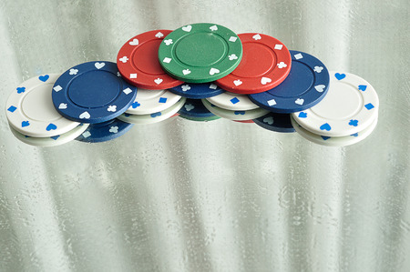 A stack of poker chips reflecting in a mirror that is stained with water drops