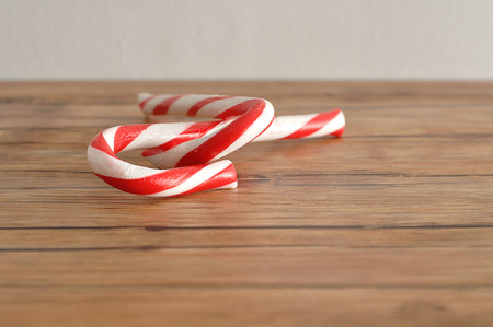 Two candy canes that is entwined together on wooden background