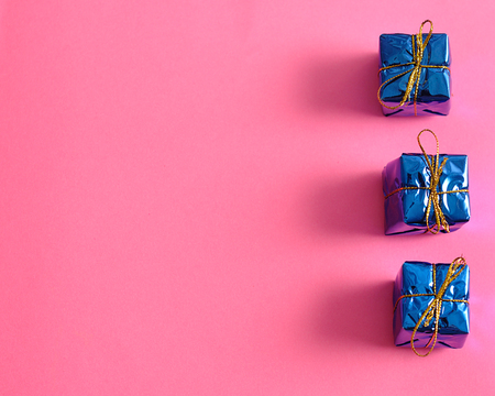 Small little gifts wrap in Shiny paper isolated on a pink background