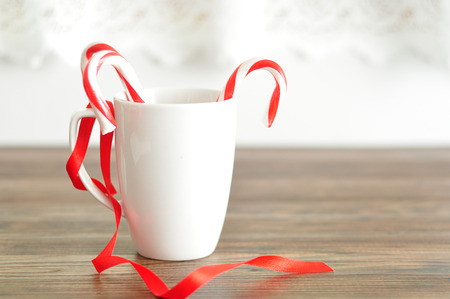 Two candy canes in a white mug with a red ribbon for decorationの写真素材